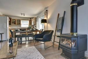 a living room with a stove and a kitchen at Chalet Émond - Petit Train du Nord, Golf et ski in Mont-Tremblant