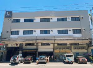 duży biały budynek z samochodami zaparkowanymi na parkingu w obiekcie GT Hotel Jaro w mieście Iloilo