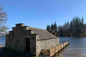 an old stone building in the water next to a dock at Potters Loft, Bowness Centre, Parking, Lake Access in Bowness-on-Windermere