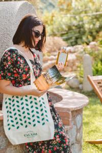Una mujer con un vestido sosteniendo una botella de miel en Calàmi - Villa Romeo - Private Apartments with Pool, Seaview & Olive Grove, en Santa Caterina Dello Ionio Marina
