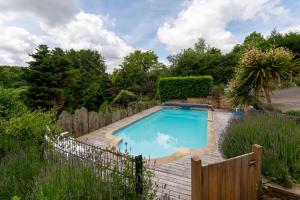 een zwembad in een tuin met een houten hek bij Les Sapins in Rochefort-en-Terre