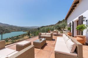 a patio with wicker furniture and a view of the water at Villa Mirador del Lago in Lecrin