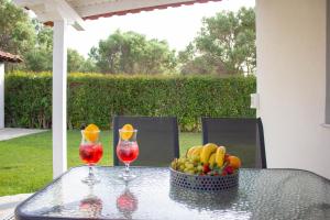 a glass table with a bowl of fruit and two wine glasses at Potamos Studios by GERANI in Órmos
