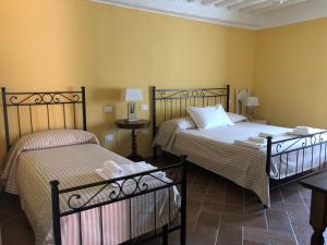 two beds in a room with yellow walls at Le Dame del Borgo in Sassetta