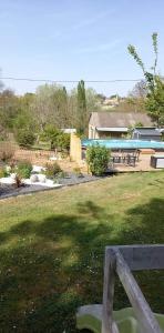 un banc dans une cour avec une maison et une piscine dans l'établissement la serenité, à Saint-Vivien-de-Monségur