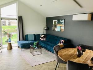 a living room with a blue couch and a table at Elegantes Chalet am Wasser mit Steg Klimaanlage Ferienhaus am See Niederlande in Kampen