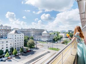 Una mujer parada en un balcón con vistas a la ciudad en Ibis Warszawa Stare Miasto en Varsovia