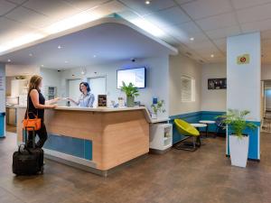 a woman standing at a counter in a waiting room at ibis budget Hotel Luzern City in Luzern