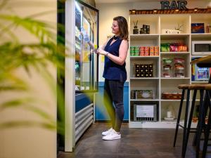 una mujer está parada frente a un refrigerador en ibis budget Hotel Luzern City en Luzern