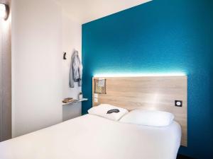 a bedroom with a white bed and a blue wall at hotelF1 Chaumont in Chaumont
