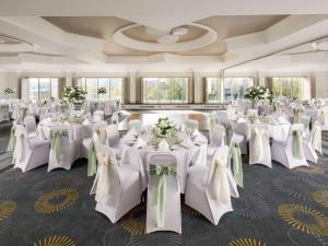 a banquet hall with white tables and chairs with flowers at Mercure Bedford Centre Hotel in Bedford