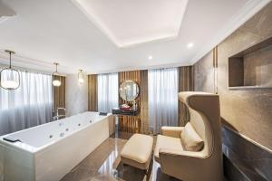 uma ampla casa de banho com uma banheira e uma cadeira. em Radisson Blu Hotel GRT, Chennai International Airport em Chennai