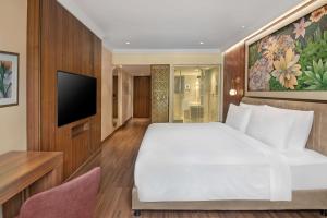 um quarto com uma grande cama branca e uma televisão em Radisson Blu Hotel GRT, Chennai International Airport em Chennai
