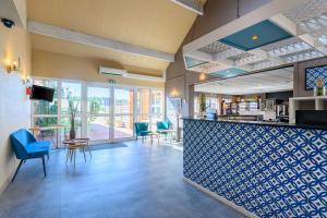 a restaurant with a bar with blue chairs at Comfort Hotel Orleans Saran in Saran