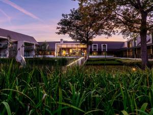 a building with tall grass in front of it at Le Domaine des Vanneaux Golf et Spa Mgallery in LʼIsle-Adam