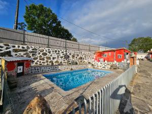 a swimming pool in front of a stone wall at Tropical Dream Farm in Vouzela