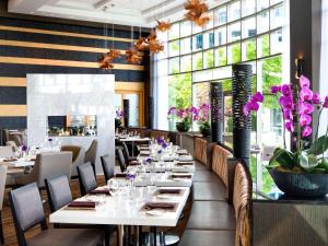 un ristorante con tavoli bianchi e fiori viola di Fairmont Waterfront a Vancouver