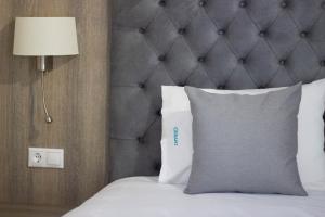 a bed with a gray headboard and a white pillow at Potamos Studios by GERANI in Órmos