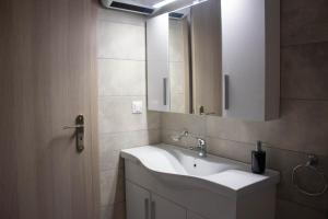 a bathroom with a white sink and a mirror at Potamos Studios by GERANI in Órmos +37 photos