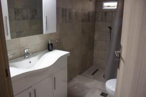 a bathroom with a white sink and a shower at Potamos Studios by GERANI in Órmos