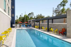 uma piscina com cadeiras amarelas e cadeiras ao lado de um edifício em Home2 Suites By Hilton Niceville Eglin Air Force Base em Niceville