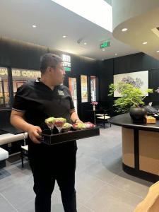 un hombre sosteniendo una bandeja de comida en un restaurante en Tangfu Boutique Hotel Nanluoguxiang Drum Tower Houhai, en Beijing