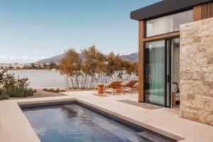 een huis met een zwembad naast een meer bij One&Only Aesthesis in Athene