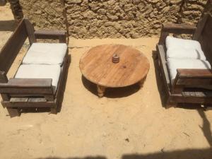 mesa de madera, 2 sillas, mesa y sofá en Tanirt ecolodge, en Siwa