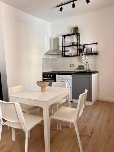 a kitchen with a white table and chairs in a room at BISCOTTAI Port Apartments in Trapani