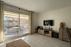 a living room with a flat screen tv and a balcony at Nice Proche Mer in Nice