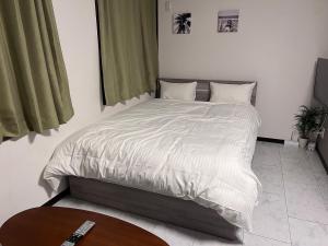 ein Schlafzimmer mit einem Bett mit einer weißen Bettdecke in der Unterkunft The Guest House Noah in Naha