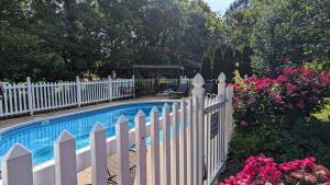 a white fence next to a swimming pool with flowers at Garden and Sea Inn in New Church