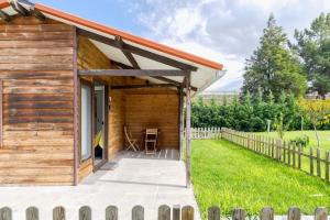 een houten hut met een veranda en groen gras bij Chalé do Vale in Pinhal Novo
