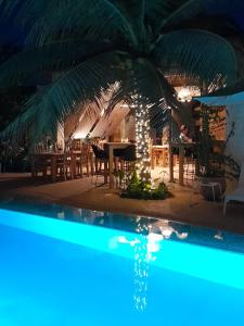 un ristorante con tavolo, palma e piscina di La Maison Vanille a Ngaparou
