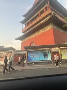 un grupo de personas caminando por una calle frente a un edificio en Tangfu Boutique Hotel Nanluoguxiang Drum Tower Houhai, en Beijing