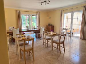 una sala da pranzo con tavoli, sedie e finestre di Vila Relaxmountain B&B a São Bartolomeu de Messines