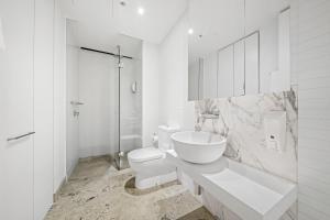 a white bathroom with a toilet and a sink at Flinders Street Apartments in Melbourne