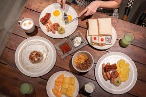 a wooden table topped with plates of breakfast food at The Quartier Hotel Phromphong - Thonglor in Bangkok