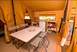 a dining room with a table and chairs in a tent at Camping Onlycamp Les Berges de l'Yonne in Coulanges-sur-Yonne