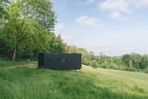 a black box sitting in the middle of a field at Offgrid Tiny Home W/ Spectacular View Of Cotswolds in Cheltenham