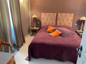1 dormitorio con 1 cama morada y 2 almohadas de color naranja en Chez nicole, en Cannes