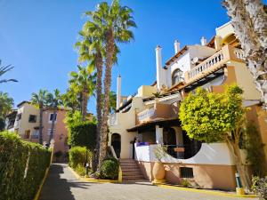 a large yellow building with palm trees in front of it at Aldea de Meer in Torrevieja