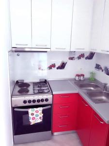 a kitchen with red cabinets and a stove and a sink at Red Sunset Apartment in Himare +5 photos