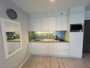 a kitchen with white cabinets and a sink at Apartment Bursztyn z ogródkiem I 250m od plażey - Apartment Bernstein mit Garten I 250m vom Strand in Pogorzelica +13 photos