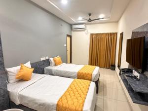 a hotel room with two beds and a flat screen tv at Hotel Aerotel,Hyderabad in Shamshabad