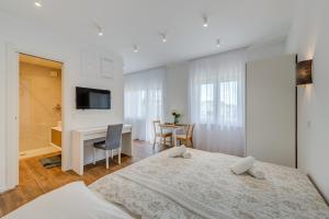 a white bedroom with a bed and a desk at Centrally located apartments, free parking in Trogir