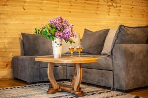 a table with two wine glasses and a vase with flowers at Sunset Cottage Kazbegi in Kazbegi