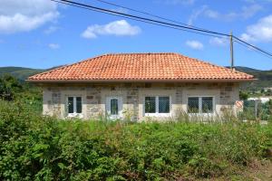 a small house with an orange tile roof at Casa de Piedra Playa de Estorde con vistas al mar in Cee