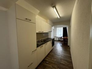 a kitchen with white cabinets and a wooden floor at Swiss Holidays-City Apartments Interlaken in Interlaken