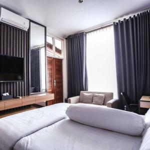 um quarto de hotel com uma cama grande e uma televisão em INEZ Homestay Prawirotaman Yogya em Timuran
